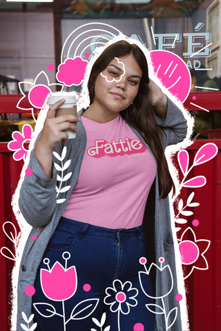 A girl in a coffee shop wearing a pink t-shirt that reads Fattie in pink in a font similar to Barbie